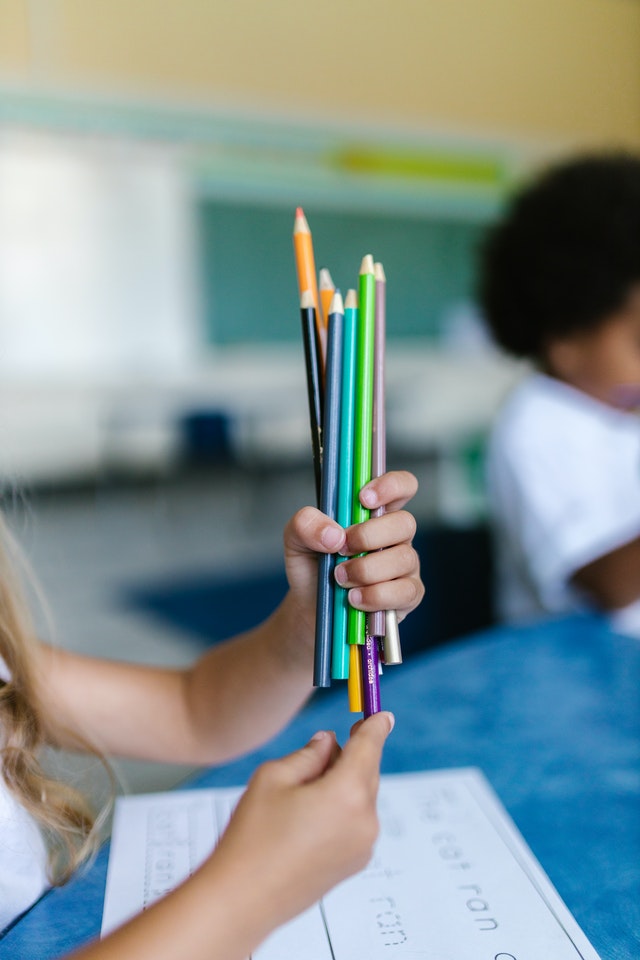 Lápices de colores en la mano de una niña estudiante